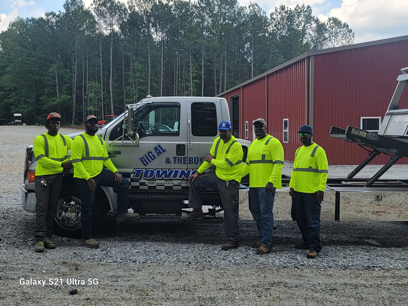 Big Al & The Boyz towing team with their tow truck in front of red building